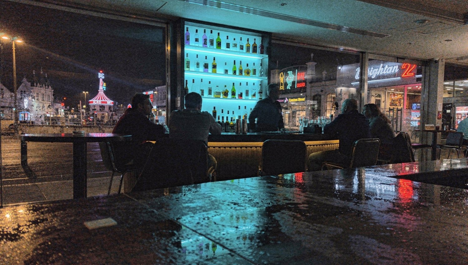 Late-night hotel bar with backlit cool-blue bottle shelf